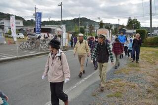 アスファルトの道の端を歩く人々。いろいろな年齢層の方がのんびりと景色を楽しみながら歩いている。