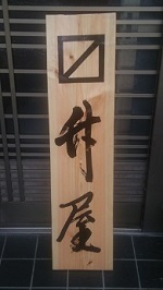 木の板に、正方形に斜めの線の引かれた記号と、升屋の漢字の書かれた看板