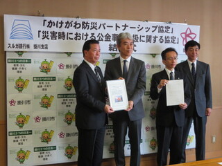協定書を手に記念撮影する松井市長とスルガ銀行の方々