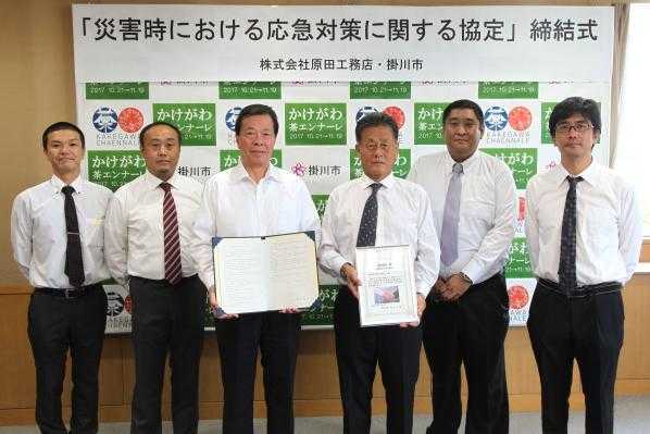 協定締結のための調印式での、市長と株式会社原田工務店男性社員5名の記念写真