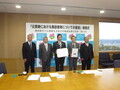 災害時における施設使用についての協定締結式で、締結書を手に記念写真を撮る掛川市長とホテル関係者ら