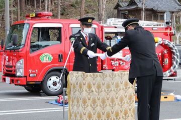 鈴木団長(左)から配属書を受け取る赤堀分団長