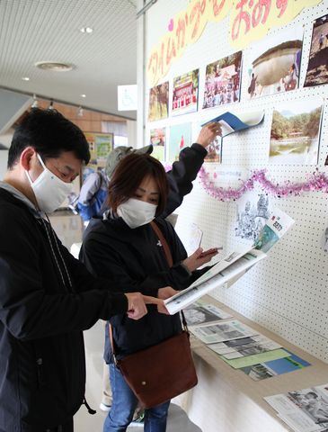 カプセルから取り出された写真を懐かしむ来場者