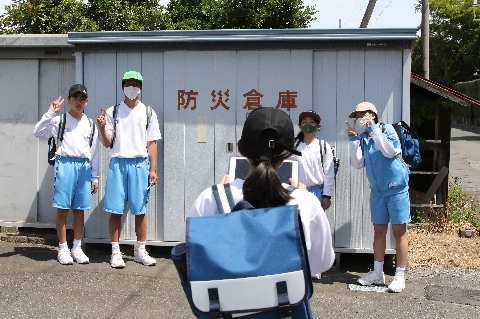 防災倉庫前で記録写真を撮る生徒たち