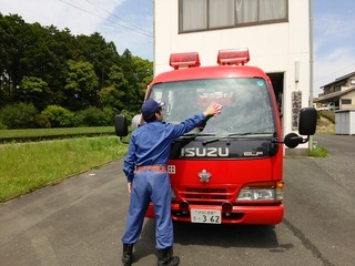 汚れてしまったポンプ車の清掃で窓を拭いている