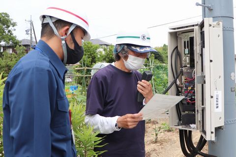 無線で地区へ呼びかける藤原会長(右)