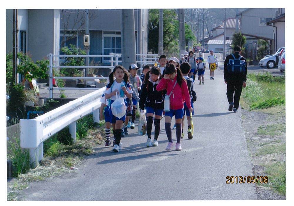 市道「一ノ坪二ノ坪線（大池地内）」施工前の道路、道幅の狭い道路を小学生が集団で歩いている
