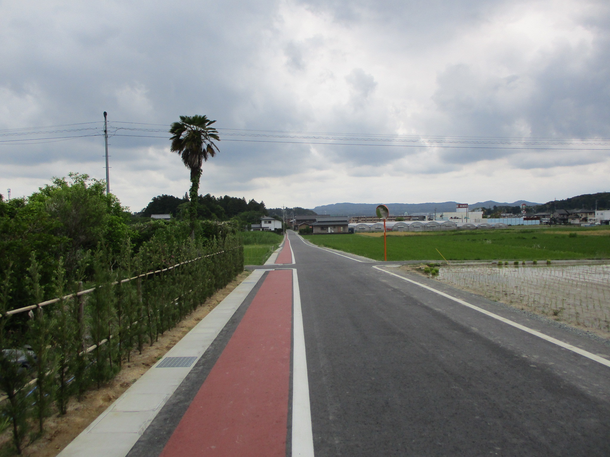 市道「西郷東側線（上西郷地内）」施工後の道路、歩道の幅が広がり、透水性舗装を施工された、歩道部分にカラー舗装されている。