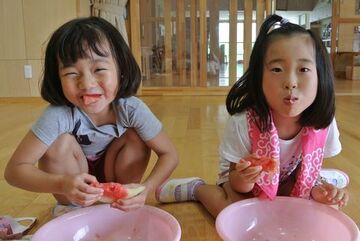 割ったすいかをおいしそうに食べる園児