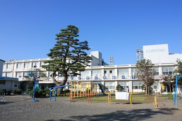 大渕小学校の外観写真で、校舎の手前にカラフルな遊具がある