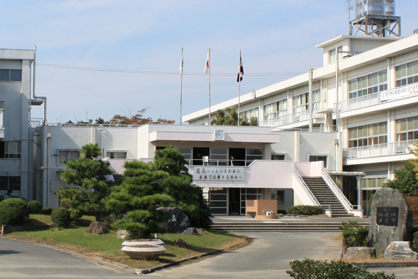 西中学校の校舎の手前に松の木や石碑がある