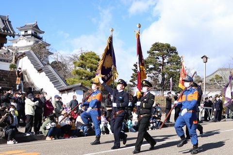 晴天のもと行進する消防団員　