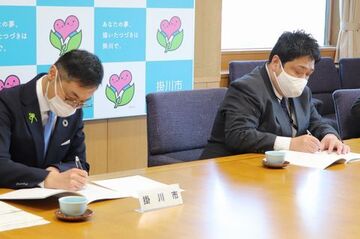 協定書にサインする野村さん(右)と久保田市長