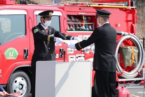 鈴木団長(左)から配属証を受け取る鈴木分団長