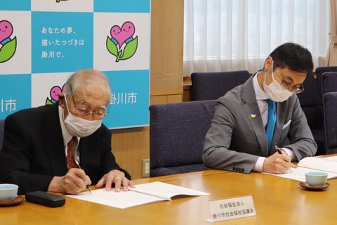 協定書に署名する中村さん(左)と久保田市長