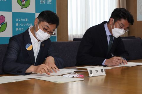 協定書に署名する小松市長(右)と久保田市長