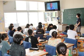 画面に映る田中さんの話を真剣に聞く児童