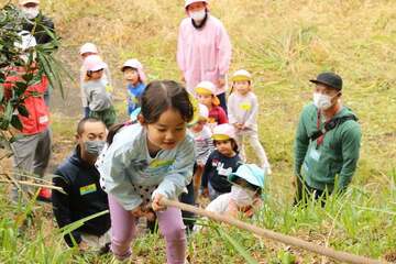 ロープを使って斜面を登る園児