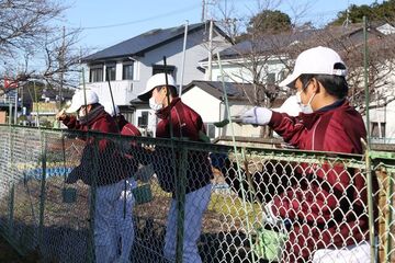 フェンスを塗りなおす野球部員