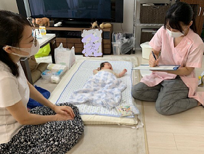 赤ちゃんが寝ている隣で、女性が母親の相談にのっている写真