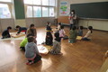 教室で、女性がカロムのやり方を子供たちに教えている写真