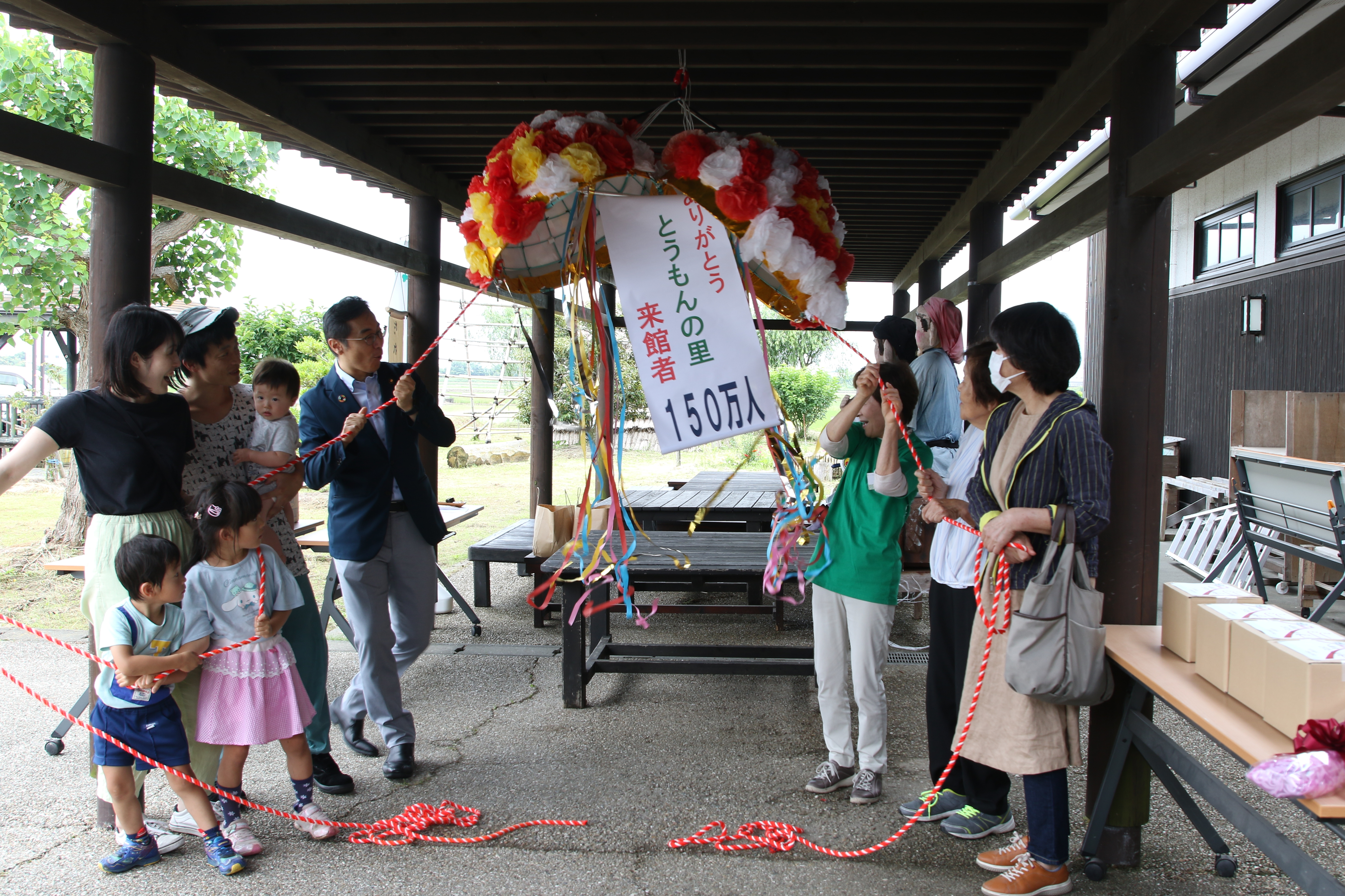 150万人記念のくす玉を開ける来館者たち（左右）と久保田市長（中央左）