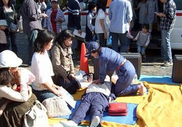 救命訓練で胸骨圧迫の仕方を実演している女性団員と参加者の女性たち