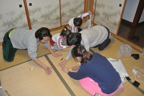 豆まきで巻いたお菓子や豆を拾う家族