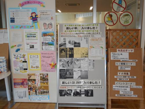 イベント情報や、入荷した本の案内等が掲示されている様子を撮った写真。ふれあいコーナーにはおたのしみ会等たくさんの案内が貼られている。その隣には、新しい本や、CDの表紙のコピーも掲示されている。
