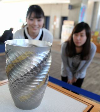 大角さんが作成した南鐐花器「海風」の展示を眺める女性2人
