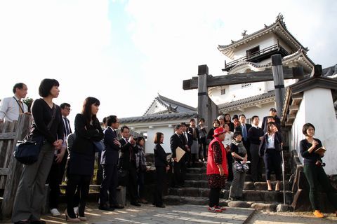 掛川城天守閣前でボランティアガイドの説明を受ける参加者らの写真