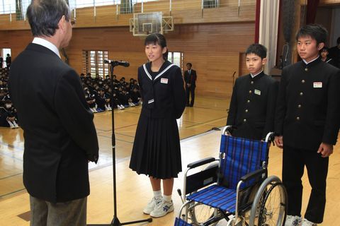 舞台の上で名倉院長に車いすを寄贈する生徒代表ら