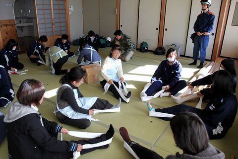 室内で日本赤十字奉仕団のメンバーから三角巾法を学ぶ中学生ら