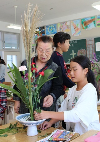 地域の方に教えていただきながら花を生けている小学生の写真