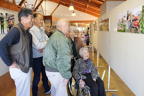 来館者と一緒に写真を眺める久保さんと鈴木さん一家の写真