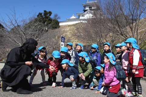 忍者ガイドからお城について学ぶ園児たちの写真