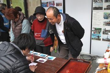 被災地への応援メッセージを書く市民を、優しく見守る市民団体のメンバー