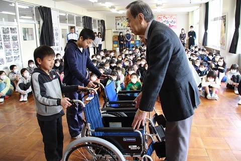 アルミ缶回収の収入で購入した車いすを贈呈する児童