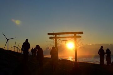 鳥居越しの初日の出を拝む人たち