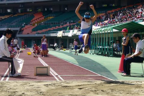 走り幅跳びの選手が声援を受けて大ジャンプをみせている瞬間の写真