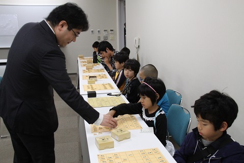 プロ棋士から多面差しで将棋の戦略を学ぶ参加者たちの写真