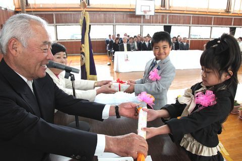 若杉会長らから傘やさるぼぼを受け取る新入学児童代表