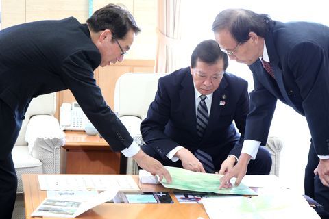 マップを広げ松井市長に整備した登山道を説明する鈴木会長らの写真