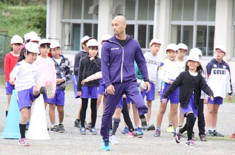 山本さんから速く走るコツを学ぶ児童たちの写真