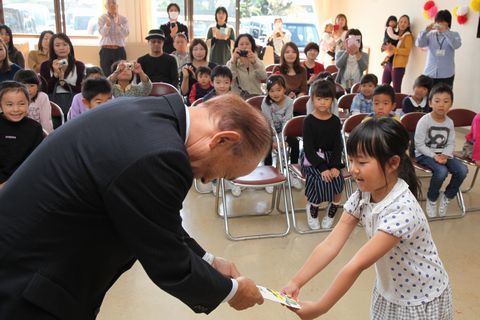 後藤会長が記念の千歳飴を児童に手渡している写真