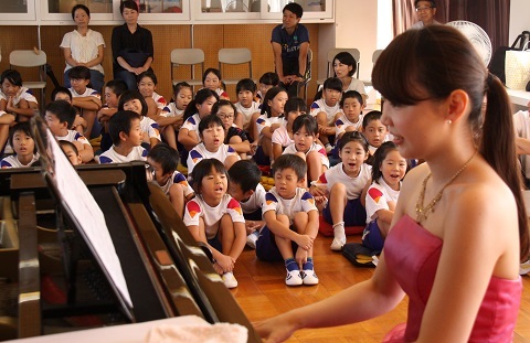 ピアノの演奏を児童たちに披露する藤田さんと演奏を聴く児童たち