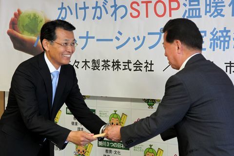 松井市長から協定書を受け取る笑顔の佐々木社長
