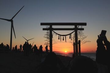 鳥居の向こうに見える初日の出を楽しむ人たち