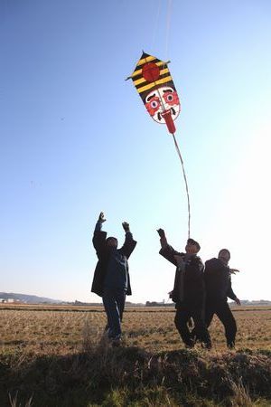 凧を持った男性達が手を放し、凧が空に舞い上がる様子を眺めている