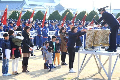 松井市長から感謝状を受け取る団員家族らと、それ見る消防団員たち